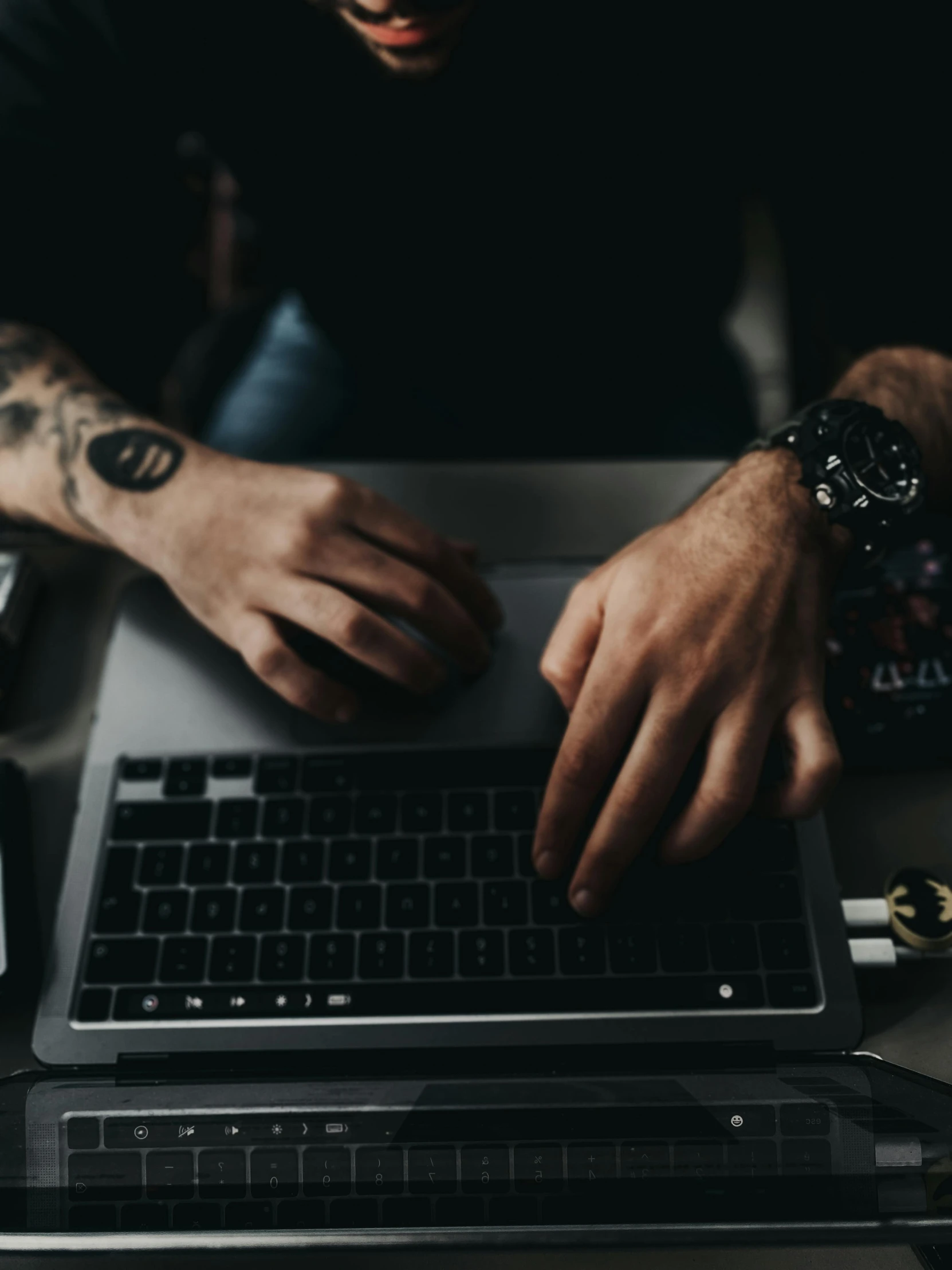 man with wrist tattoo typing on his laptop