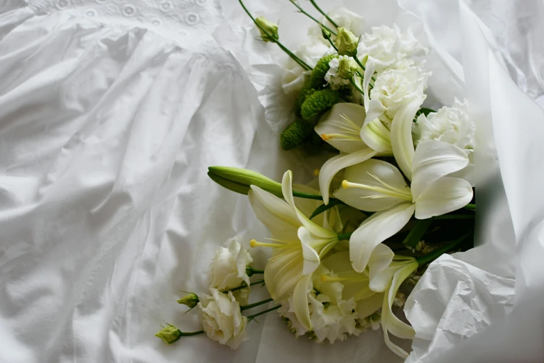 a bouquet of flowers laying on a white bed sheet