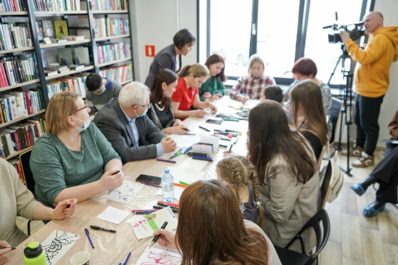 people sitting at a table in front of books in a liry