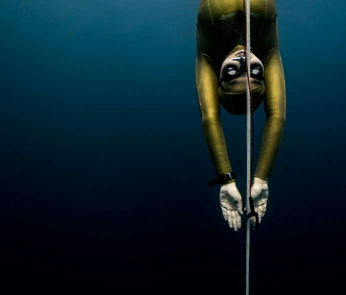 man diving in the ocean with a pole and rope