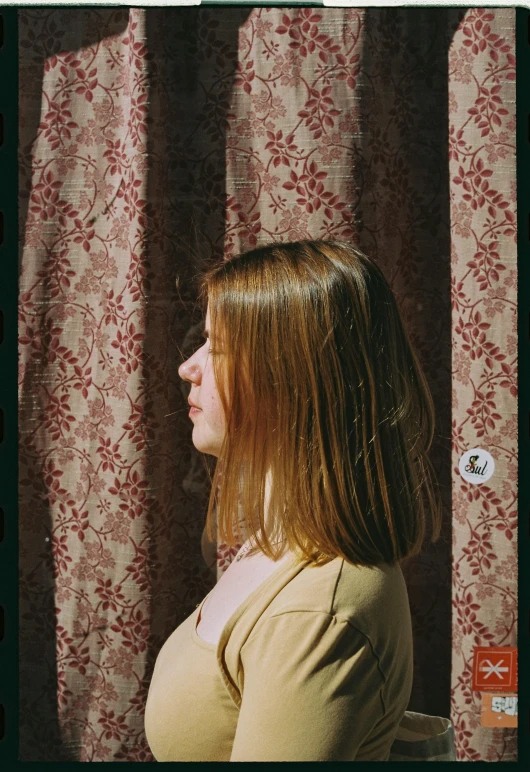 a girl looking off to the side against red and white curtains