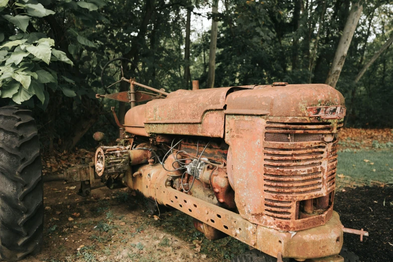 an old rusted tractor is parked next to a tree