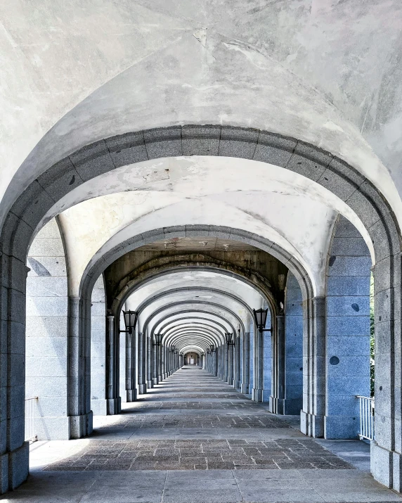 arched concrete corridor with blue columns and white walls