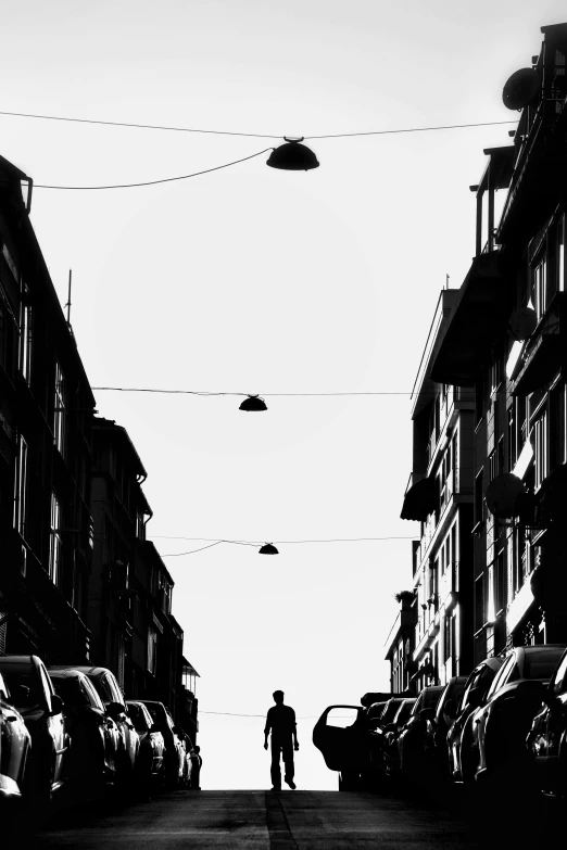 a silhouette of a person walking down an empty city street