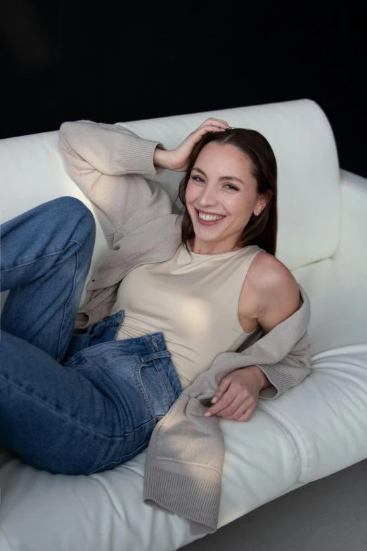 a woman sitting on top of a white sofa smiling