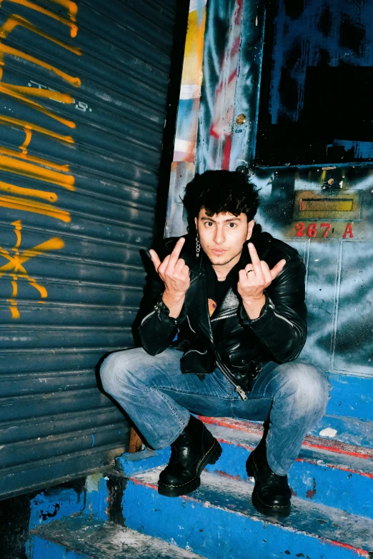 a man posing in front of a building with graffiti written on it