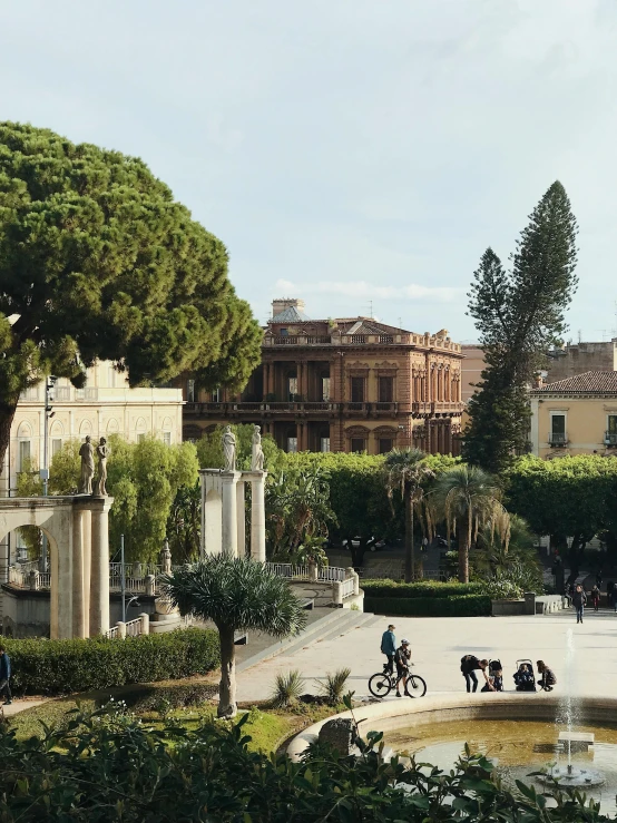 people are gathered around a fountain with people on their bikes