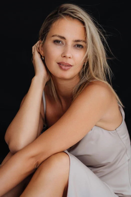 a blonde haired girl wearing a dress sitting on a floor