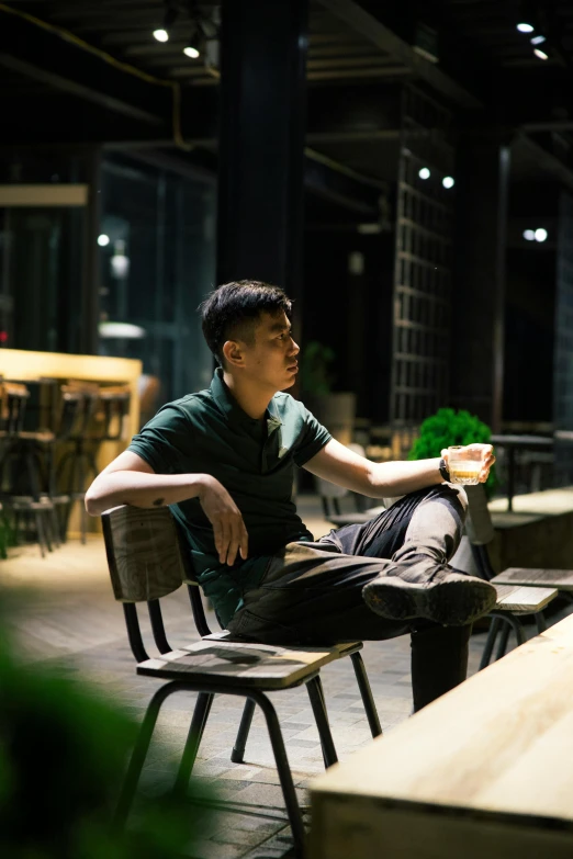 a man sits on a chair in the dark, while eating pizza