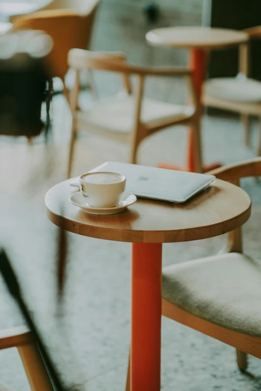 a small wooden table with a laptop and a tea cup on top