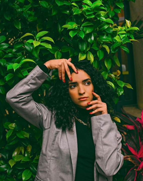 a woman leaning on her fingers in front of green foliage