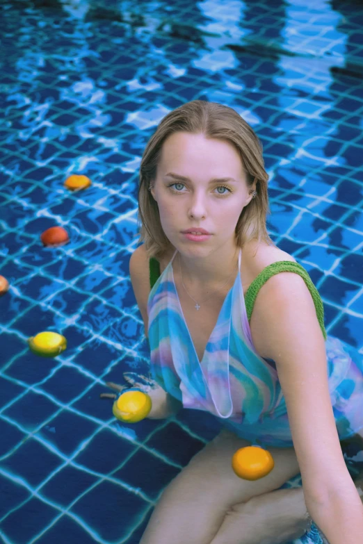 a young woman in a tank top is sitting near a pool