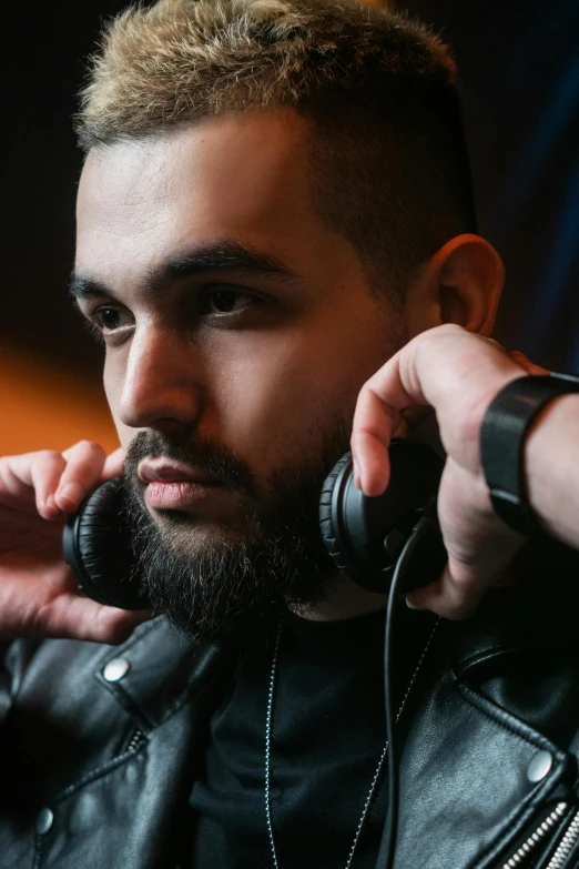 a man holding on to ear headphones while wearing a leather jacket