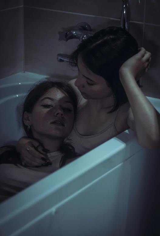 two women laying down in the tub together