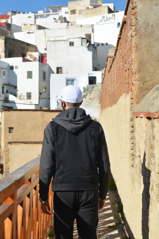 a man walks down a walkway while looking down the hill