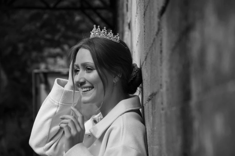 woman in white jacket and tiara against wall smiling