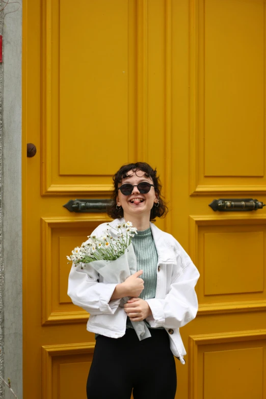 a woman in glasses holding flowers and smiling