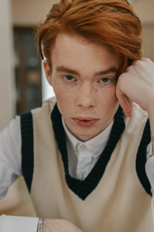 a young man wearing a vest and celet holding his hand over his hair