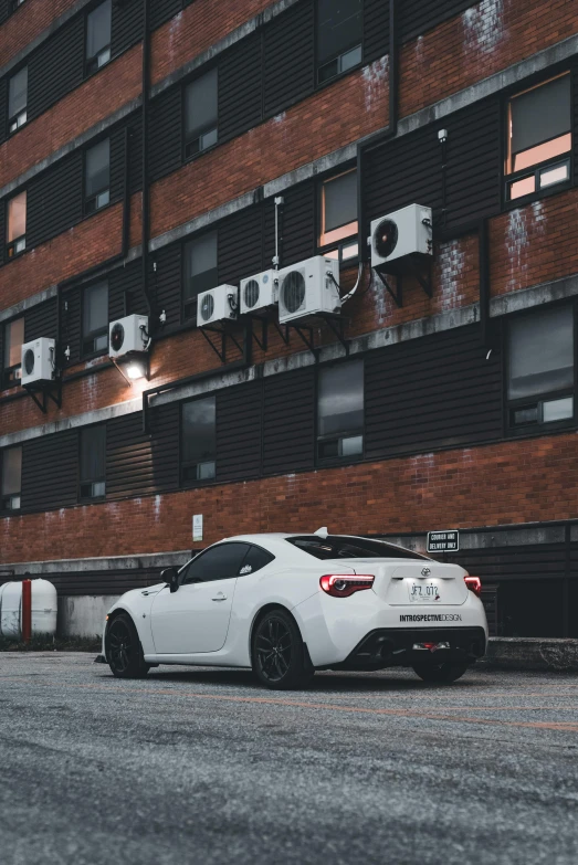 the car is parked by the large building with cameras on it