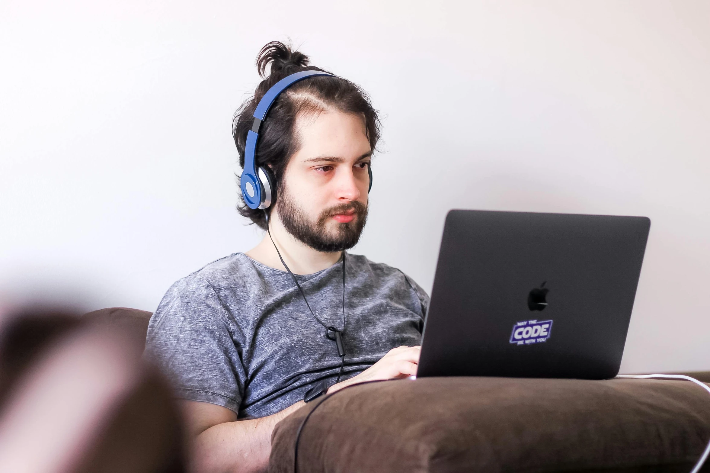 man wearing headphones while using laptop on couch