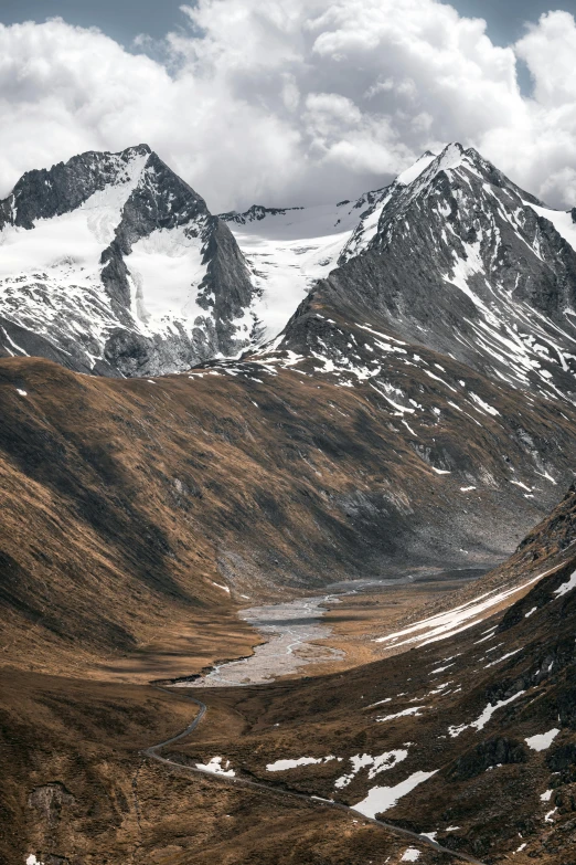 some white snow and brown grass and mountains