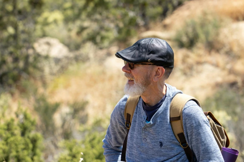 an older man with a grey beard hiking through mountains