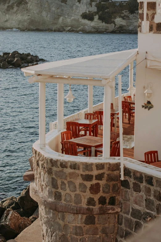 tables and chairs sit near the water at a rest stop