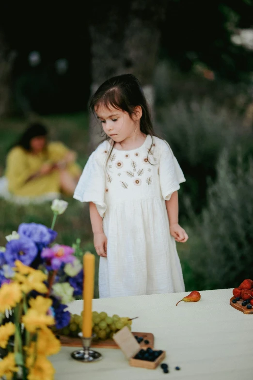 a little girl is standing next to a table