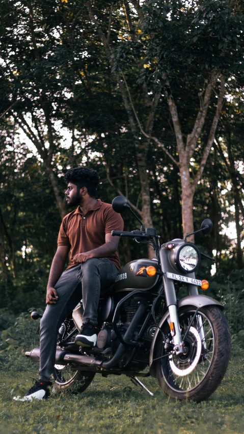 the man sits on top of his motorcycle, which is parked in a field