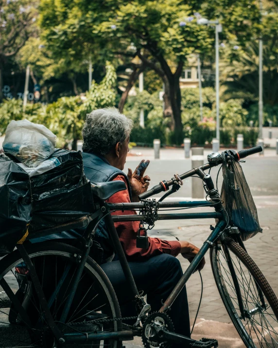 man sitting on bicycle looking at cell phone