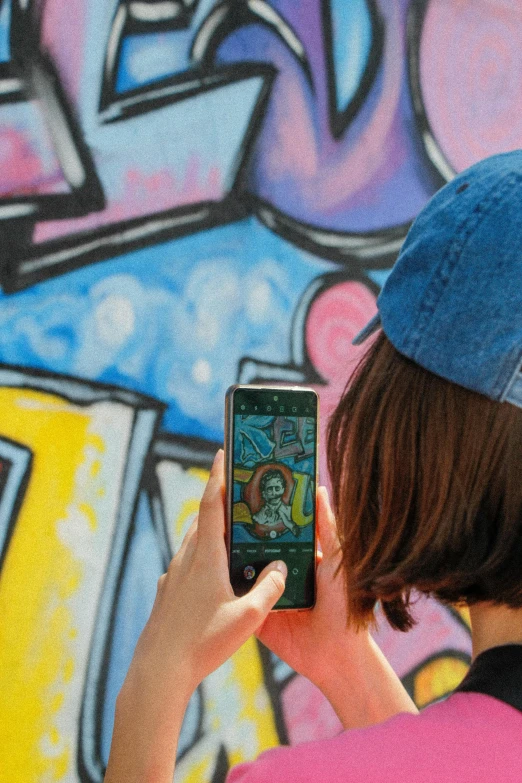 someone wearing a beanie taking a picture of a wall with graffiti