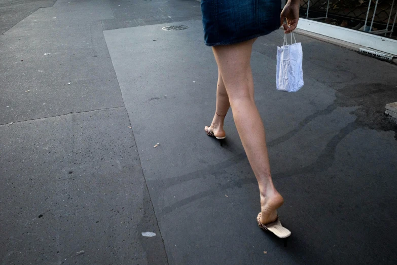the legs of a woman walking down the sidewalk