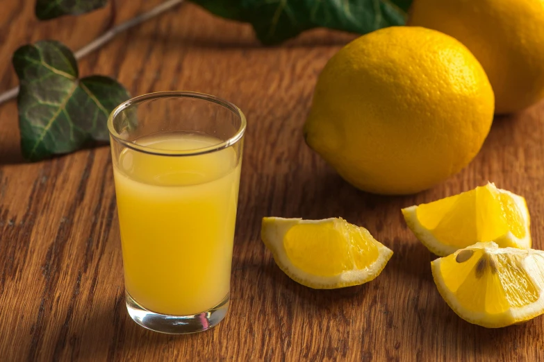 a cut up lemon next to a glass full of juice