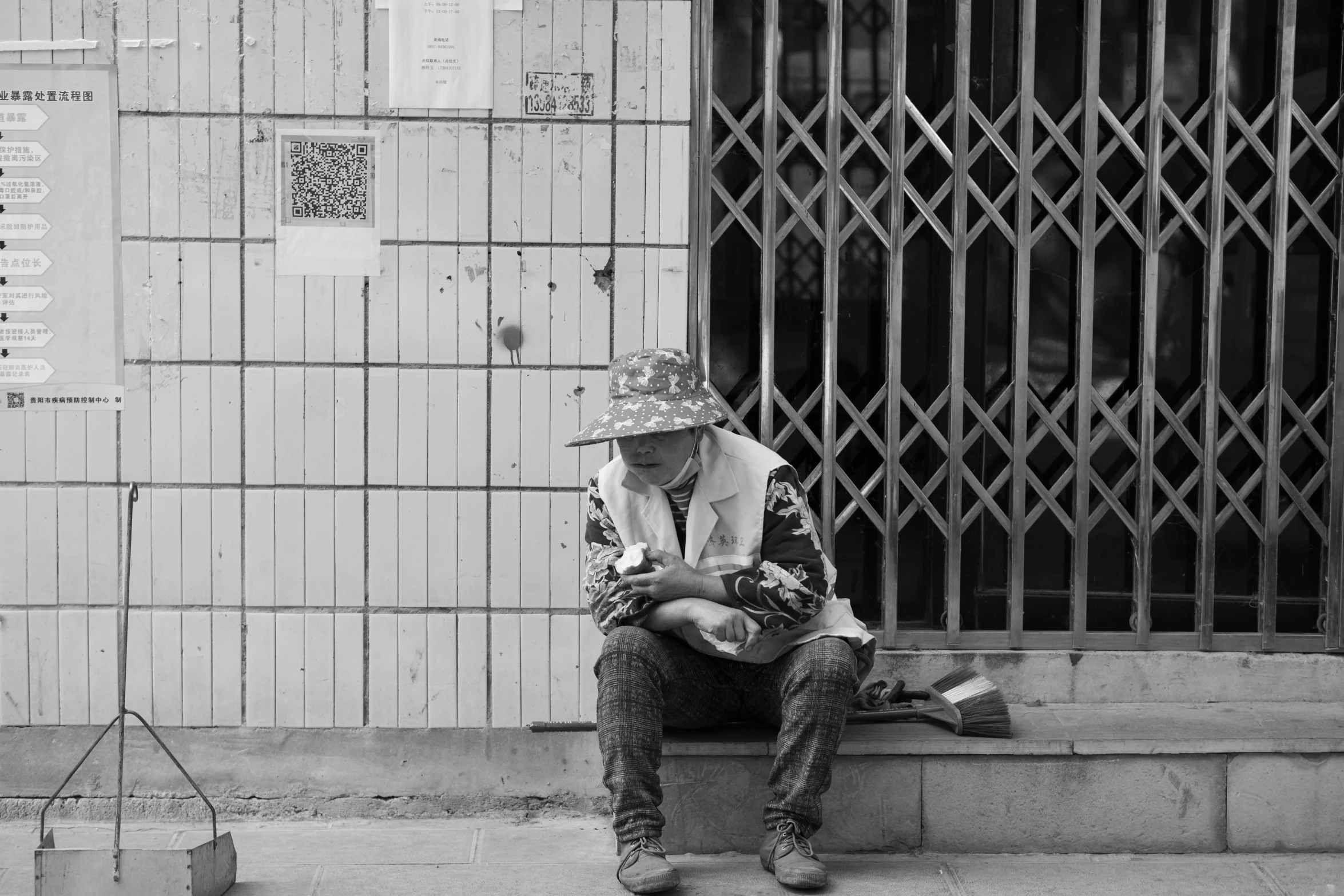 a person sitting on the steps near a building with bars