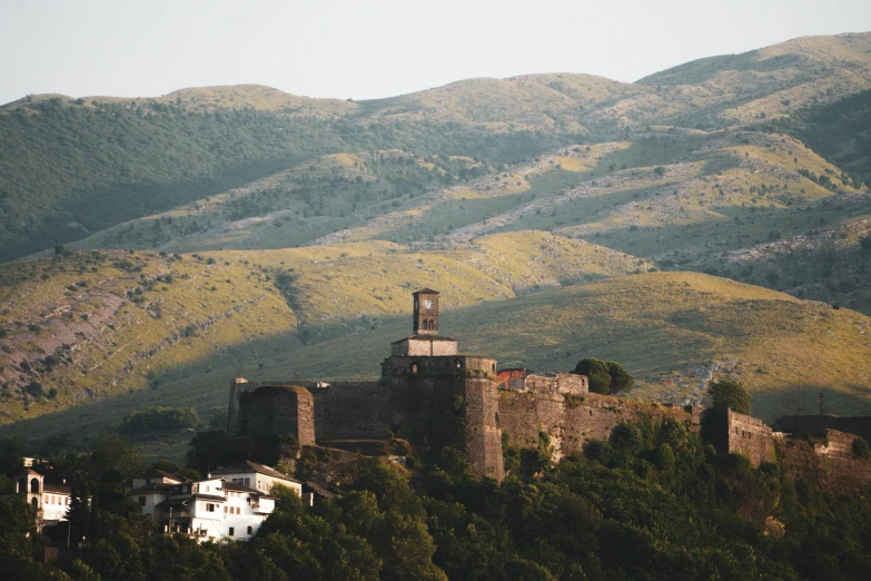 a castle in the hills with a forest behind it