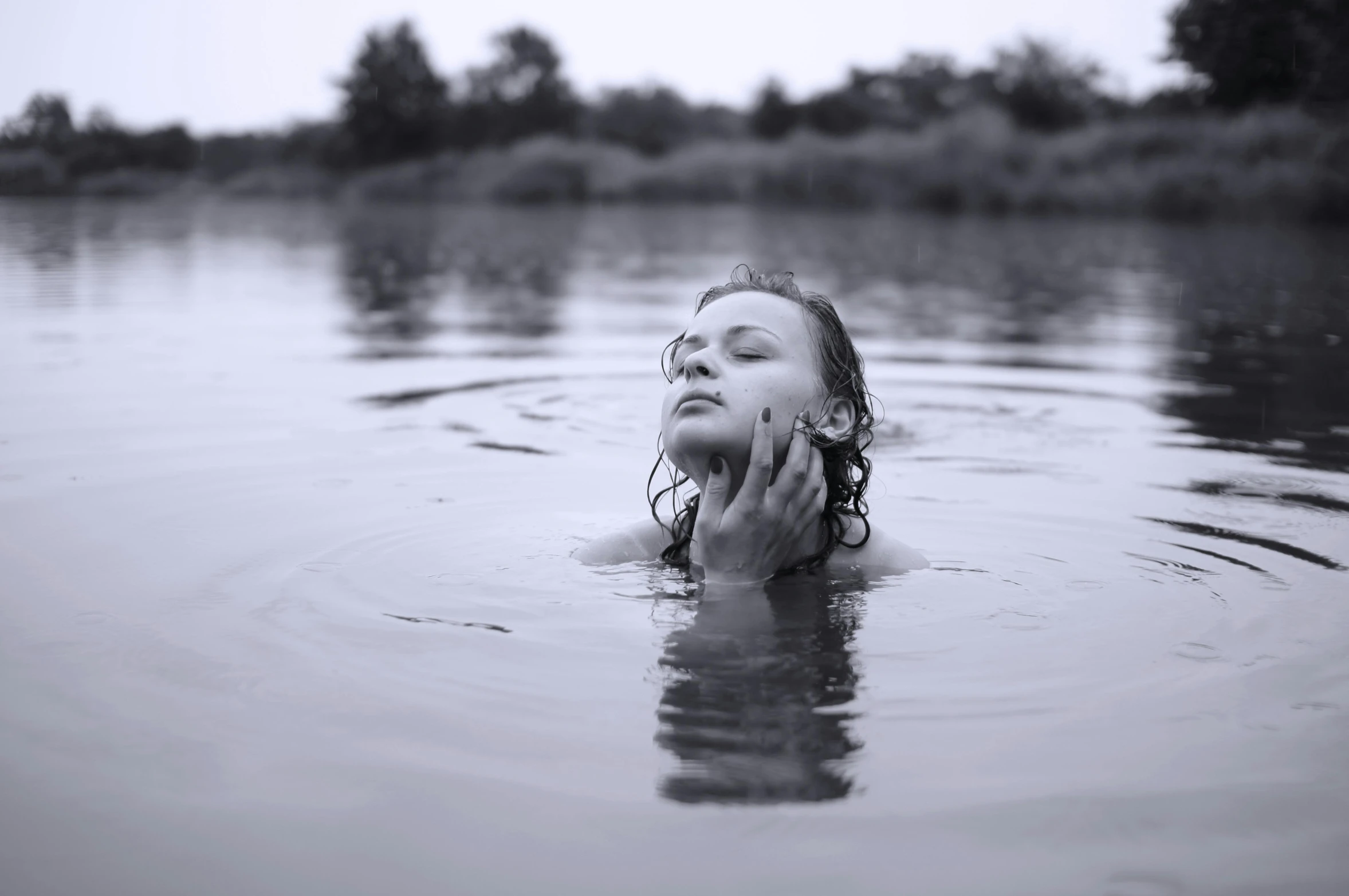 a woman is swimming in a lake while smoking a cigarette