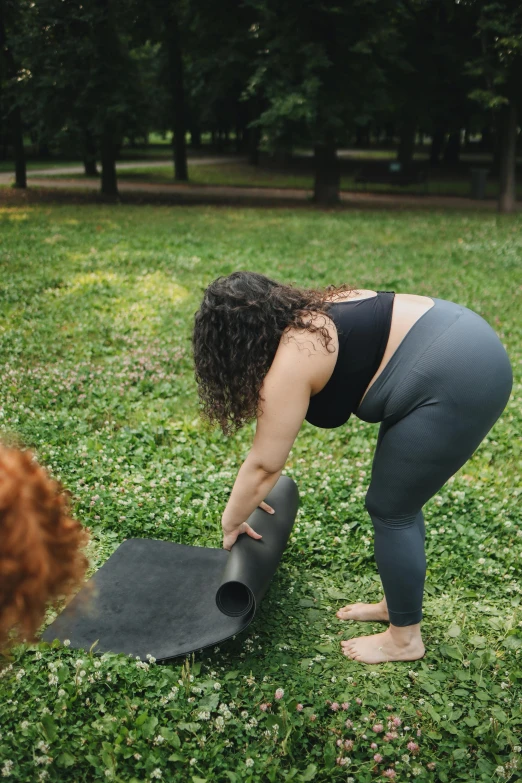 woman with black top bending over in grassy area