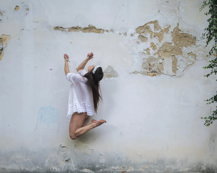 a woman leaning up against a wall with one leg in the air