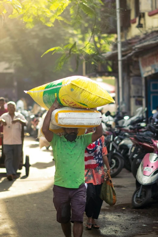 a person carrying soing on his head walking down the road