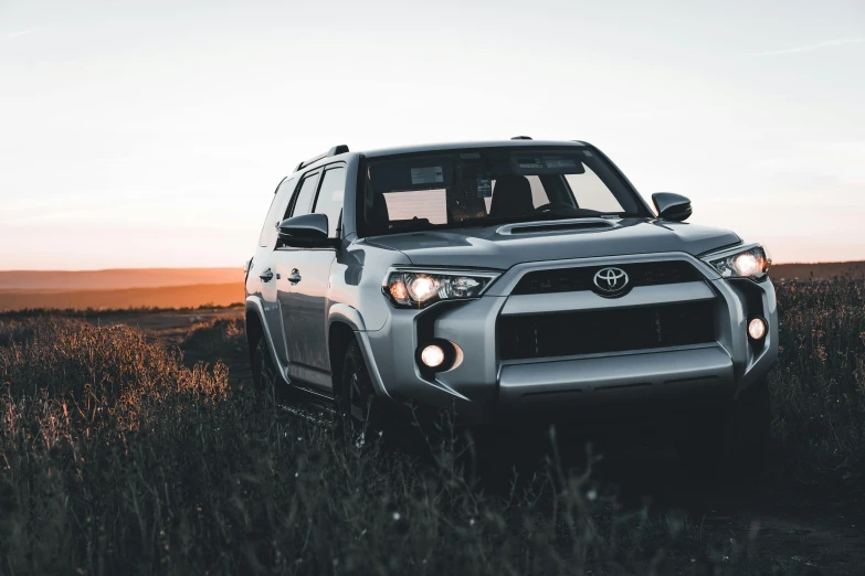 a silver toyota is parked in the middle of a field