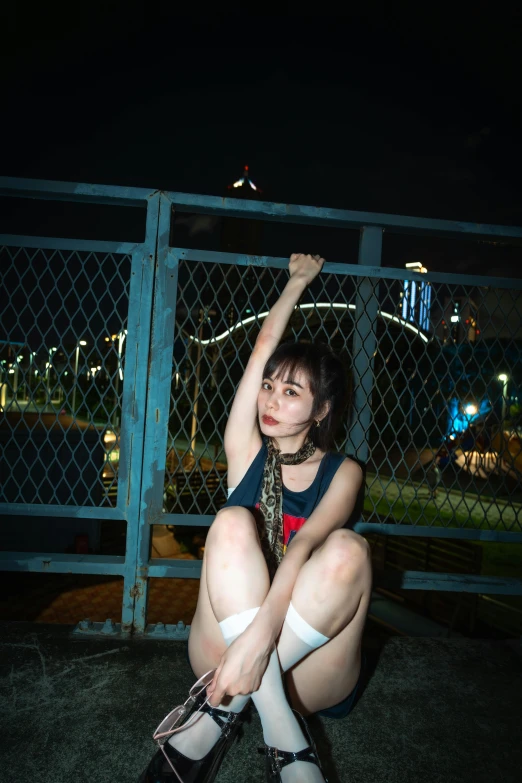 a girl kneeling on the ground by a fence