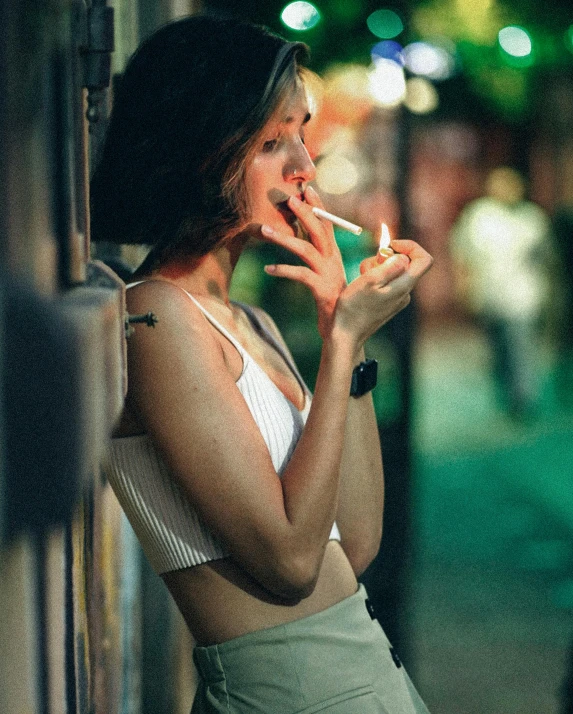 a woman smoking a cigarette next to a wall