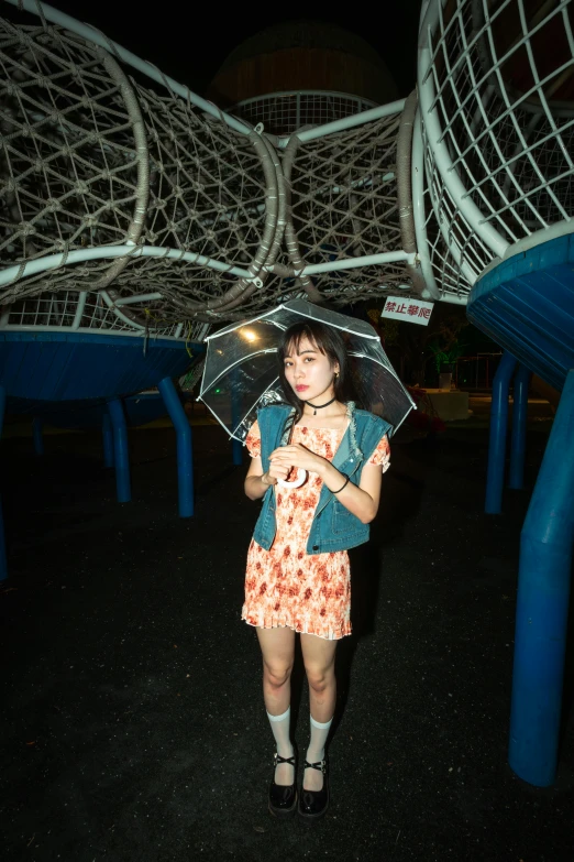 a girl stands under an umbrella outside in the rain