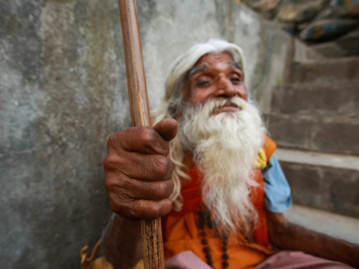 the elderly man with long white beard is holding a cane