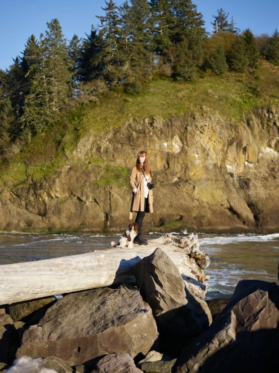 the young woman is standing on a rock near a river