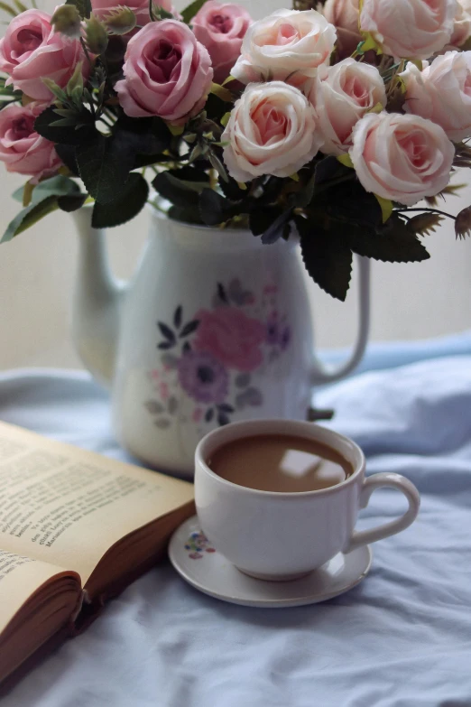 a white vase filled with flowers next to a cup of coffee