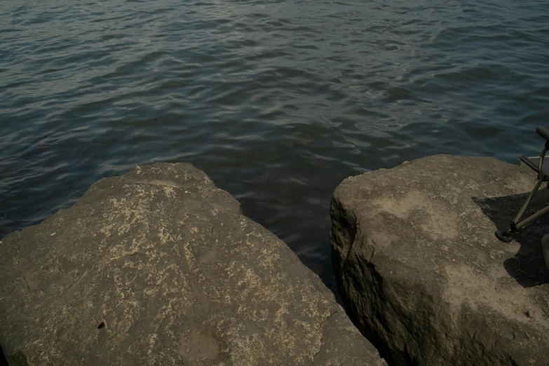 two rocks are placed near the water to hold a chair