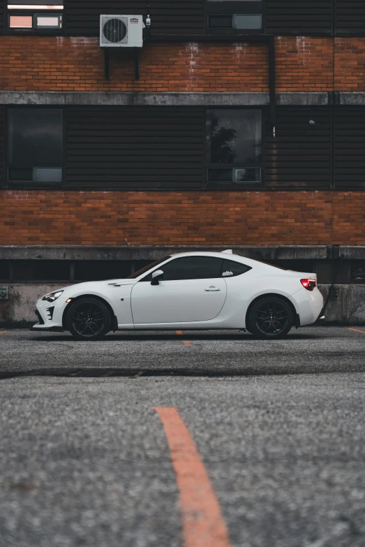 the white sports car is parked by a building