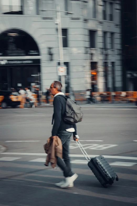 a man walking across the street pulling some luggage