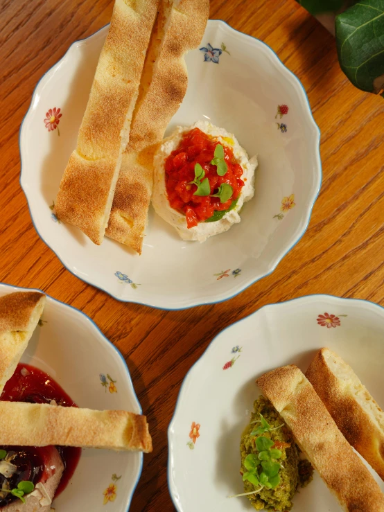 a few white plates holding food that includes salads and other condiments